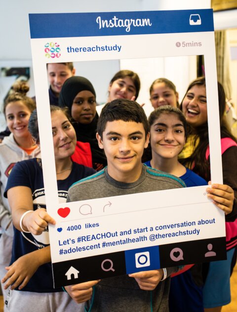 Picture of children smiling from behind a cutout template of an instagram post border