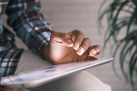 Close up photo of a person working on an ipad, showing their hand working on the ipad