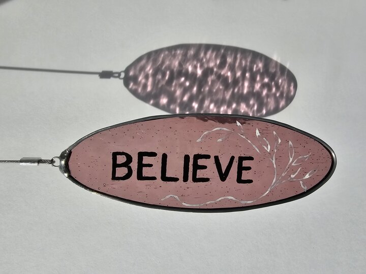 Painted glass with the text "believe"