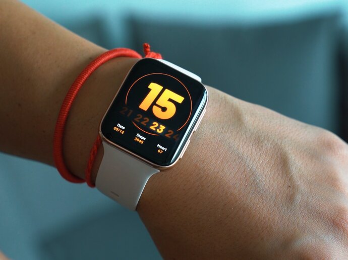 A wrist wearing a fitness watch displaying the time