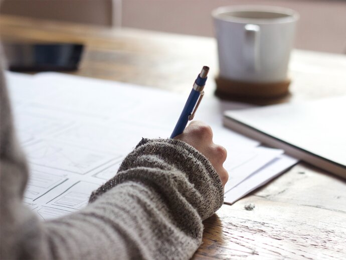 Picture of someone writing with a pen and paper