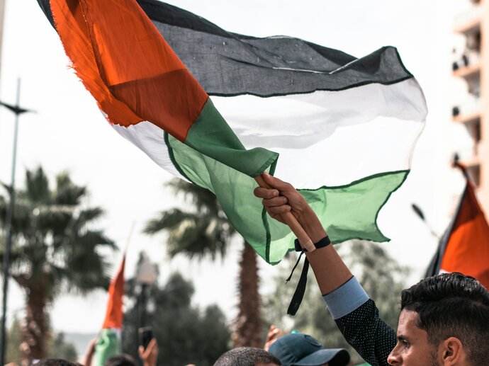 Image by Hossam Bouaza via Unsplash A man holding aloft a palestinian flag