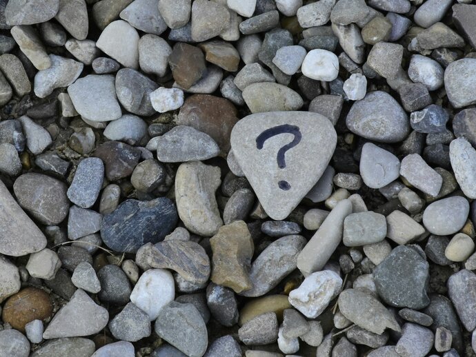 Photo by Ana Municio on Unsplash Pebbles on a beach, one of which has a question mark drawn on it