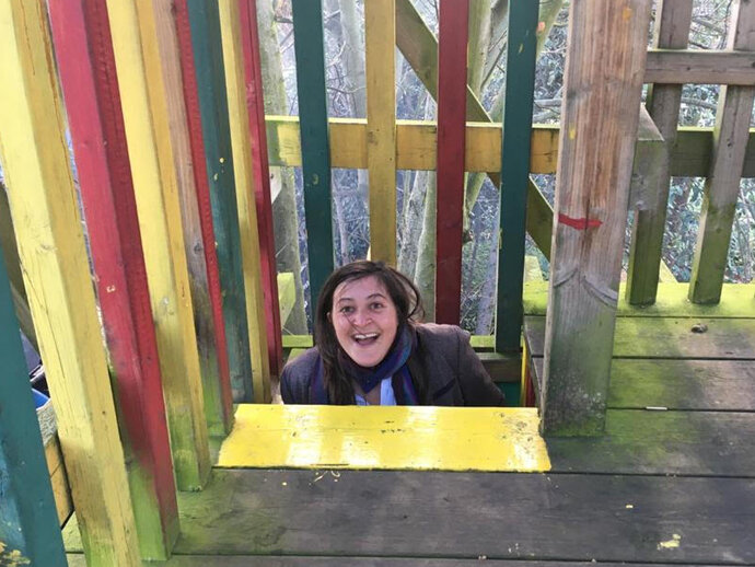 Photo of Dr Hannah Cowan emerging from a childen's climbing frame in a playpark