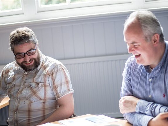 Two men sit at a table talking