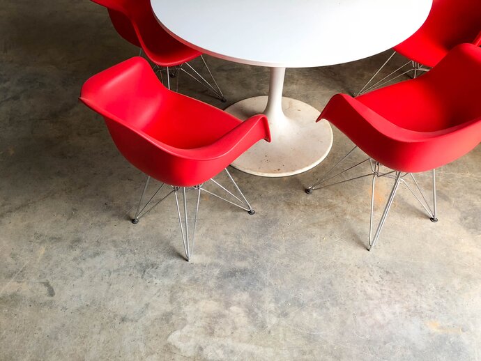 Red chairs sit around a small white table