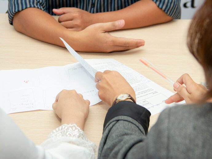 three people discussing a document between them on a table