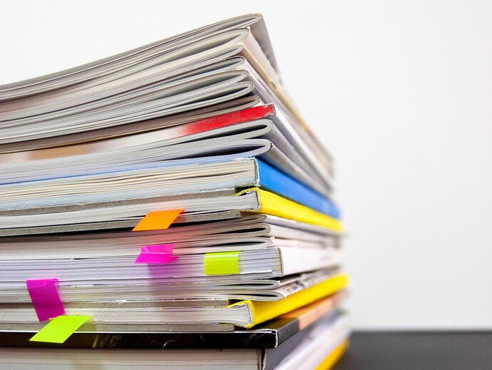 Photo of a stack of magazines, with post-it note bookmarks in several of them