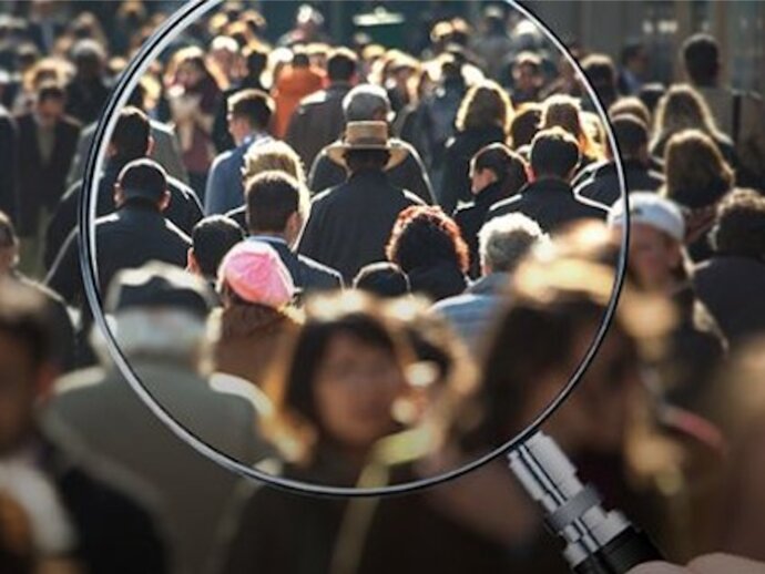 Magnifying glass bringing a picture of a crowd of people into focus