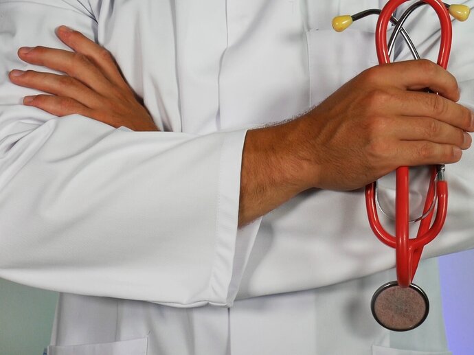 A doctor in a white lab coat holding a red stethoscope