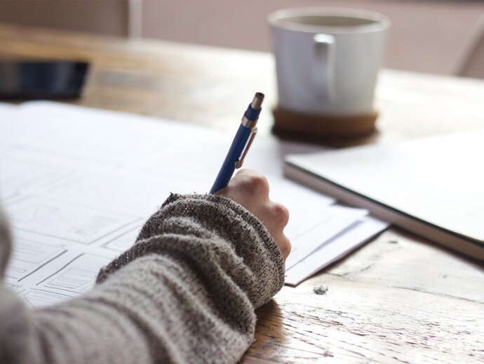 Picture of someone writing with a pen and paper