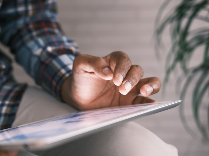 Close up photo of a person working on an ipad, showing their hand working on the ipad