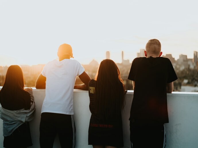 Image by Devin Avery via Unsplash a racially diverse group of  young people standing looking out at a cityscape