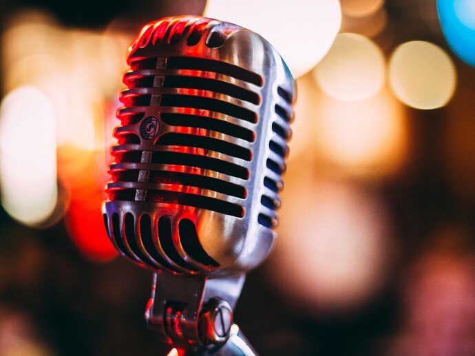 Close up of an old fashioned metal microphone with lots of out of focus lights in the background.