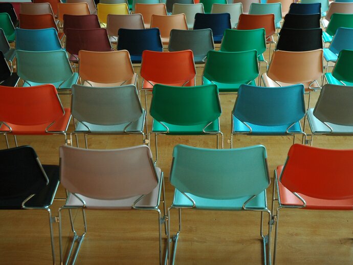 Several rows of colourful plastic chairs, viewed from behind