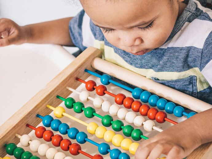 Image by Luis Arias via Unsplash Small child playing with an abacus