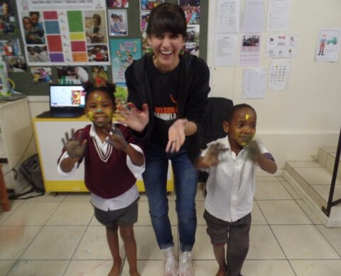 Photo of Sharli with two children as part of her early career work in South Africa