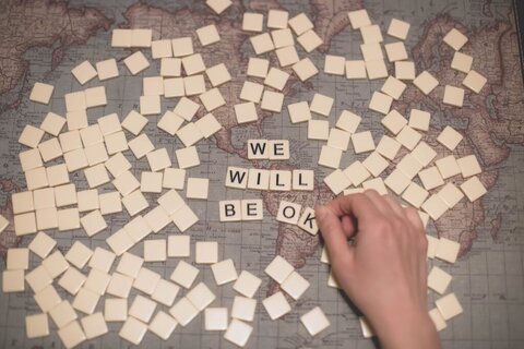 Picture of scrabble tiles spelling out "we will be ok" over a map of the world