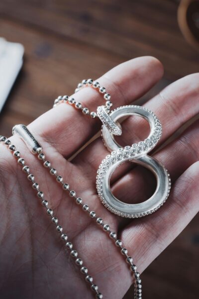 A necklace in the shape of the infinity symbol made out of tentacles, held in someones hand