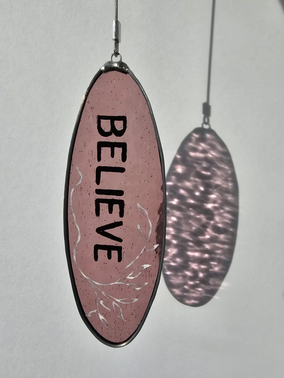 Painted glass with the text "believe"