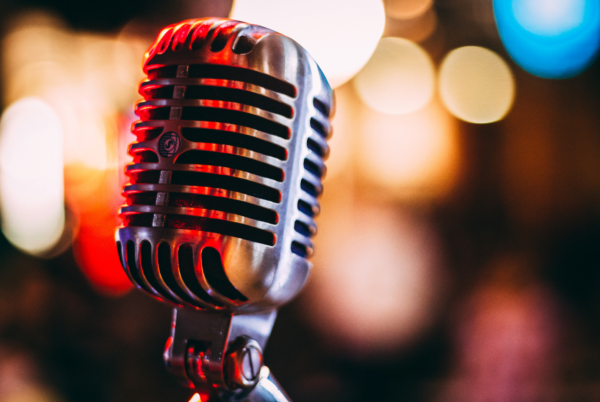 Close up of an old fashioned metal microphone with lots of out of focus lights in the background.