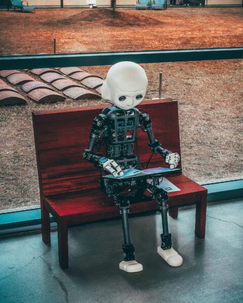 A cute little humanoid robot holding a digital book