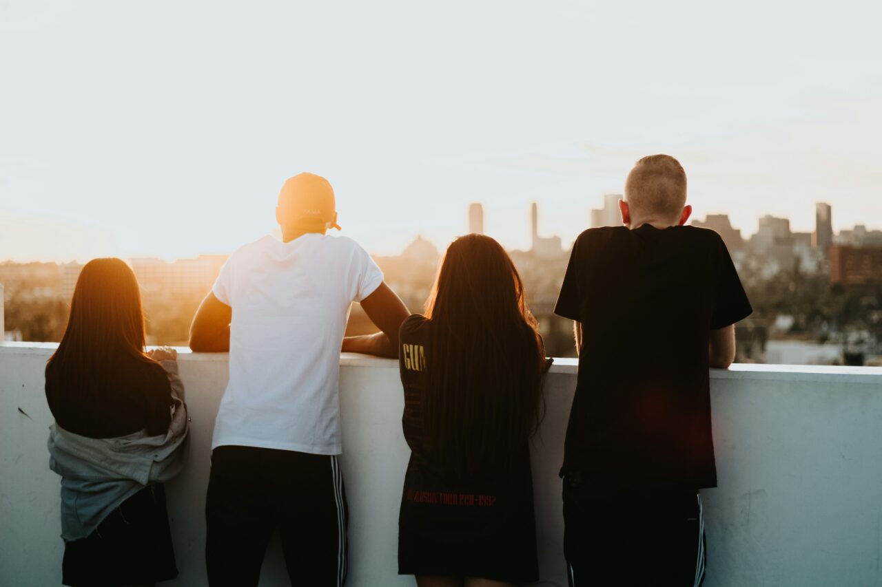 a racially diverse group of young people standing looking out at a cityscape