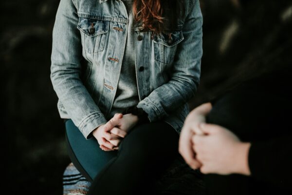 two people sitting opposite each other with hands folded on their laps