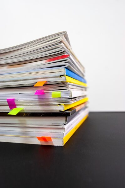 Photo of a stack of magazines, with post-it note bookmarks in several of them